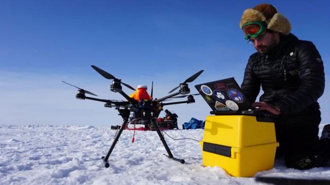 一名阿拉斯加无人机系统整合中心的研究生正在操作空拍机，针对紊乱的冰原进行测绘，协助当地猎人开辟雪地摩托车路线以便前往捕鲸。 PHOTOGRAPH BY ALAS