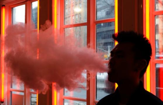 图中男子吸食电子烟，喷出蒸气。