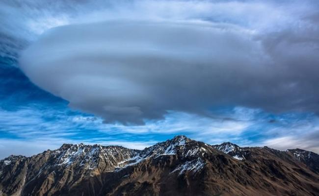 雪山上有一片云，形状似UFO。