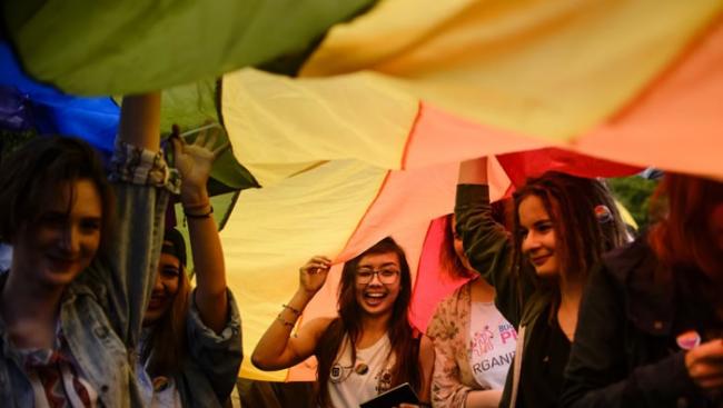 众女郎举起巨型彩虹旗游行。