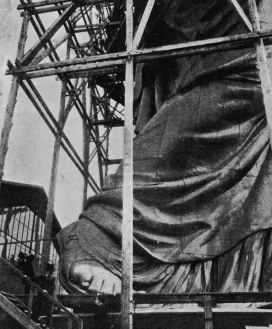 在自由女神像被运往美国前，游人们来到尚未完工的雕塑面前合影留念。