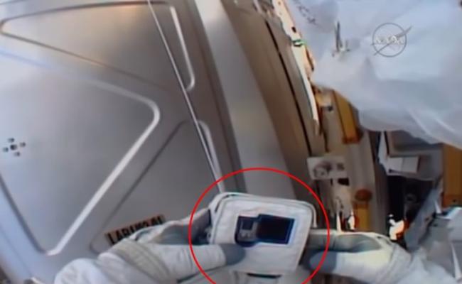 宇航员手执没记忆卡的Go Pro相机（红圈），向控制中心求救。