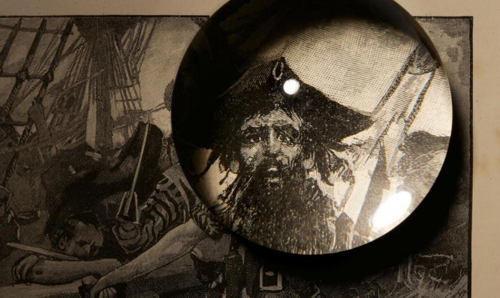 一幅19世纪的版画，描绘的是1718年海盗黑胡子在北卡罗来纳州的奥克拉科克攻击一艘英国单桅帆船。 Photography by Robert Clark, Na