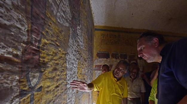 在图坦卡门陵墓内，埃及古文物部长曼杜•爱尔达玛迪以及瑞福斯检视可能藏有暗门的一段墓壁。 Photograph by Brando Quilici,