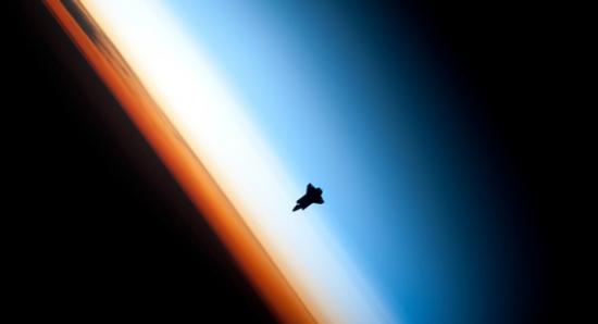 国际空间站2010年拍摄的奋进号太空飞船的图片。奋进号太空飞船正在逐渐靠近国际空间站，它与地球大气层背景形成强烈对比。宇宙飞船背后的蓝色层是地球大气平流层，下方