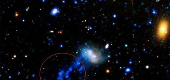 天文学家最近观测到一个正在大量失去气体物质的星系（红圈中显示的是该星系流出的气体物质形成的尾巴）