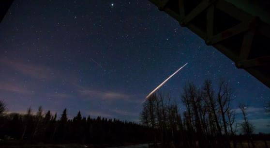 加拿大摄影师拍得照片，显示夜空中有明亮光芒划过。