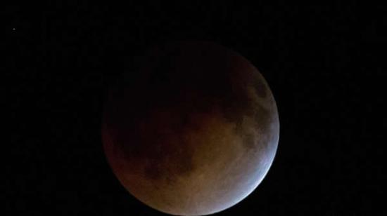 这是4月15日在墨西哥首都墨西哥城拍摄的月全食过程中的月亮