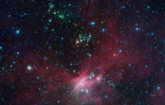 在美国宇航局的斯皮策太空望远镜拍摄的照片中，科学家发现数十颗新生恒星从它们的多尘“茧”向外喷射物质流。这幅图像展示了大犬星座附近的一片区域，绿色和蓝色区域为斯皮