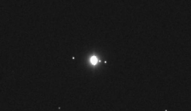 图中显示“奥里西斯- REx”探测器最新拍摄的图像，中心位置是木星，右侧是木卫一和木卫二，左侧是木卫四，木卫三是木星第四大卫星，也出现在这张图像中，但由于运行至