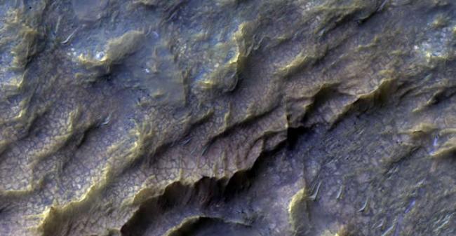 影像中浅红色的鳞状结构，是在很久以前由流水形塑的火星岩盘，形成含有黏土的岩石。目前我们还不清楚火星上的岩石和流水，是如何产生交互作用的。 PHOTOGRAPH