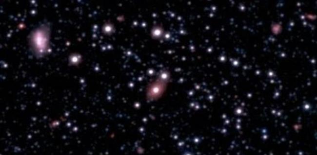 新发现的星系SAGE0536AGN(图像中央粉色椭圆星系)被发现其中心存在一个超大质量黑洞，并且其质量远超天文学家们的预期。这个黑洞的成长速度似乎远远超出了它的