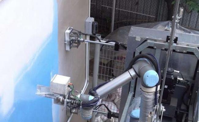 机器人用机械臂的喷射器射出油漆，翻新外墙髹漆。
