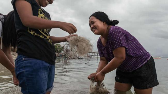 菲律宾妇女正在清洁要卖到国外再造的废弃渔网。 PHOTOGRAPH BY HANNAH REYES MORALES, NATIONAL GEOGRAPHIC