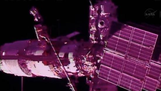 国际空间站外，一位宇航员在骑在起重机吊臂上进行工作。