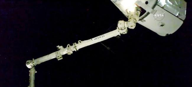 宇航员操纵巨型机械臂将补给胶囊抓住。