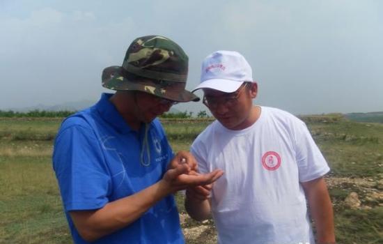 河北省文物研究所泥河湾考古队领队王法岗(左)向公众介绍石器情况