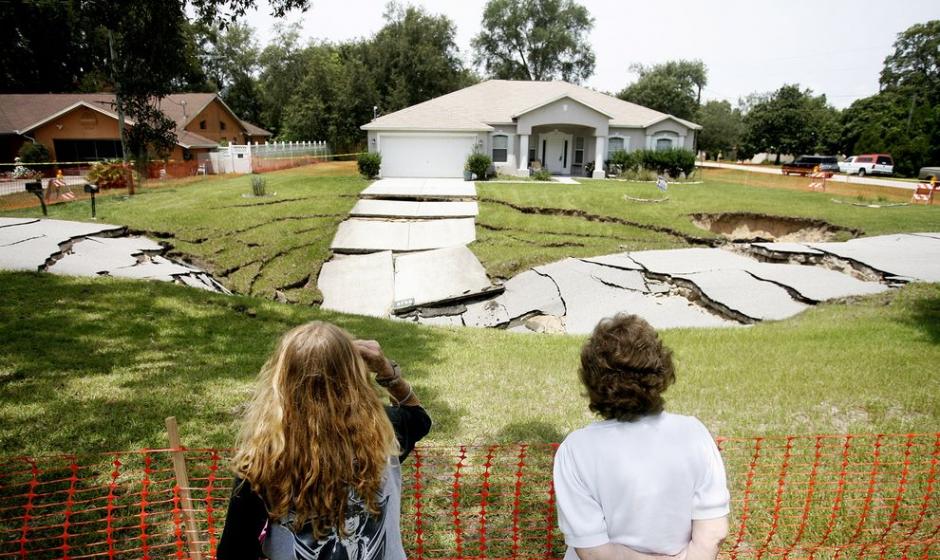 2014年7月19日，一个巨大的渗穴出现在美国佛罗里达州斯普林丘的道路上。好奇的居民在一旁探看。