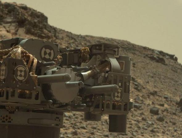 图中，好奇号的机械臂刚刚完成一次火星表面的钻探作业