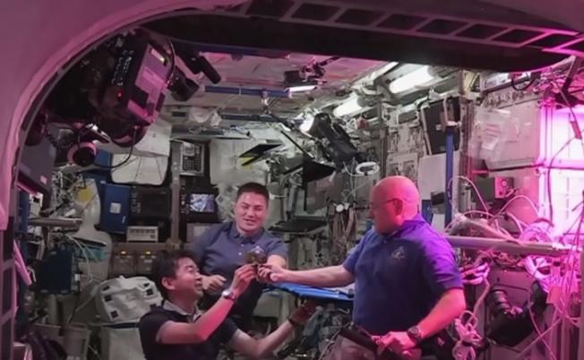 3名太空人在进食“太空生菜”前，先以生菜互相“祝酒”庆祝。