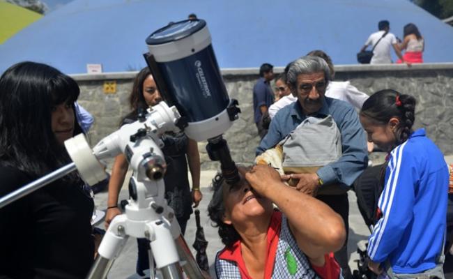 墨西哥籍游客一尝用特别望远镜观看日全食的滋味。