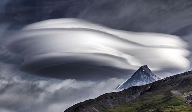 这朵巨大的荚状云是在俄罗斯东部一座山顶部形成的，照片背景中还可以看到正常的风暴云。