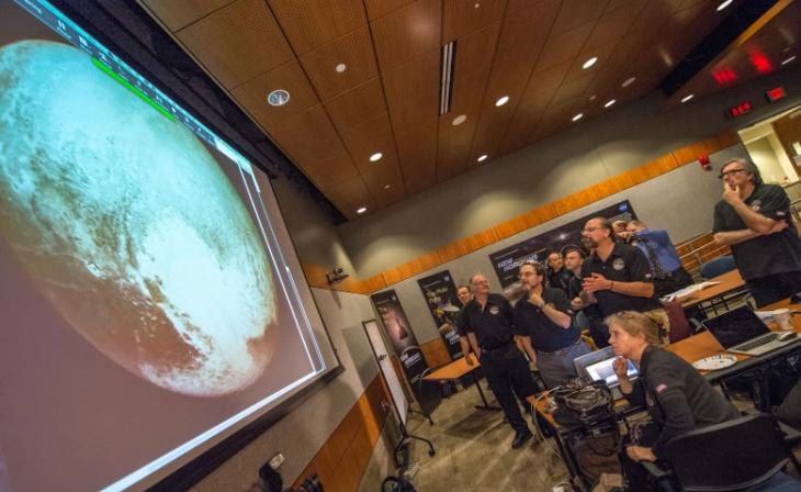 新视野号科学小组成员聚精会神观看探测器见到的冥王星最光亮的照片。