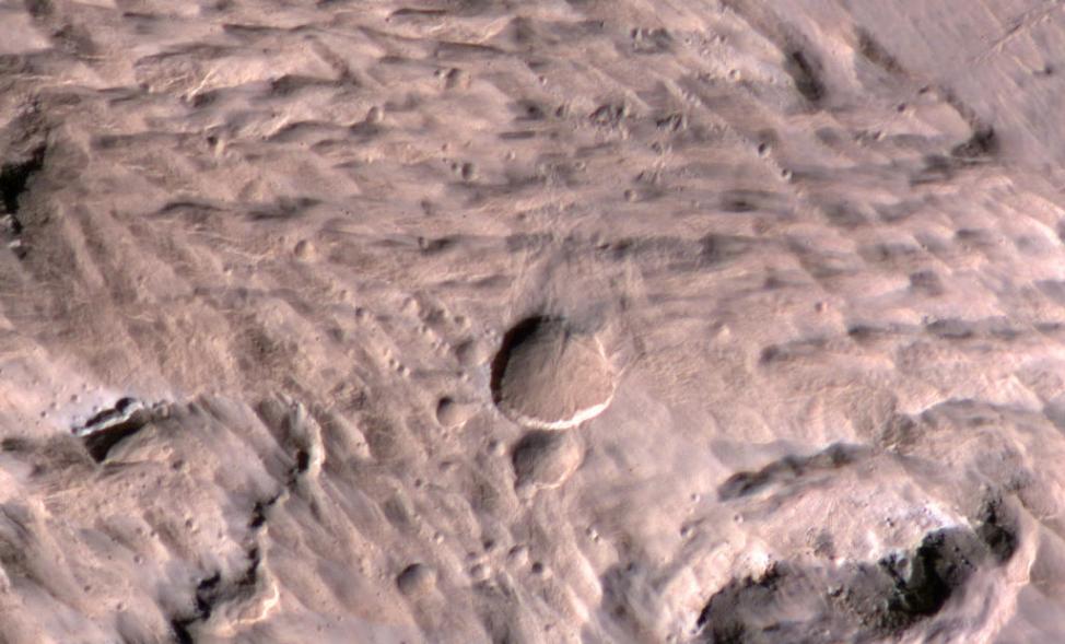 科学家发现火星表面的一个新陨石坑，它是由2012年3月的一次撞击产生的。这张图片是由美国宇航局勘测轨道飞行器上的高分辨率科学试验仪器拍摄的。