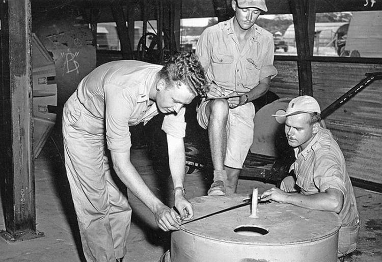 一群人正在日本南部马里亚纳群岛的提尼安岛上对原子弹外壳进行检查，美军从此地起飞袭击广岛和长崎