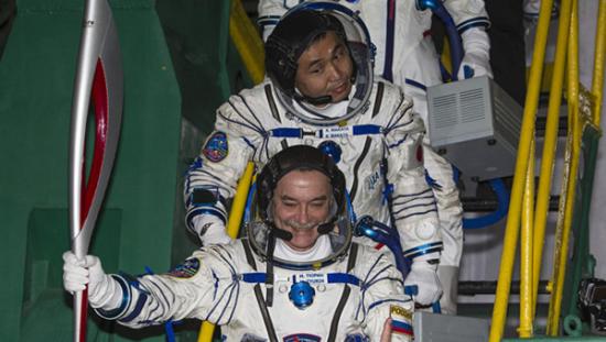 11月7日，俄罗斯宇航员秋林（前）手持索契冬奥会火炬准备前往国际空间站。