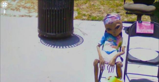 一名“外星人”坐在路旁呆看经过的汽车。