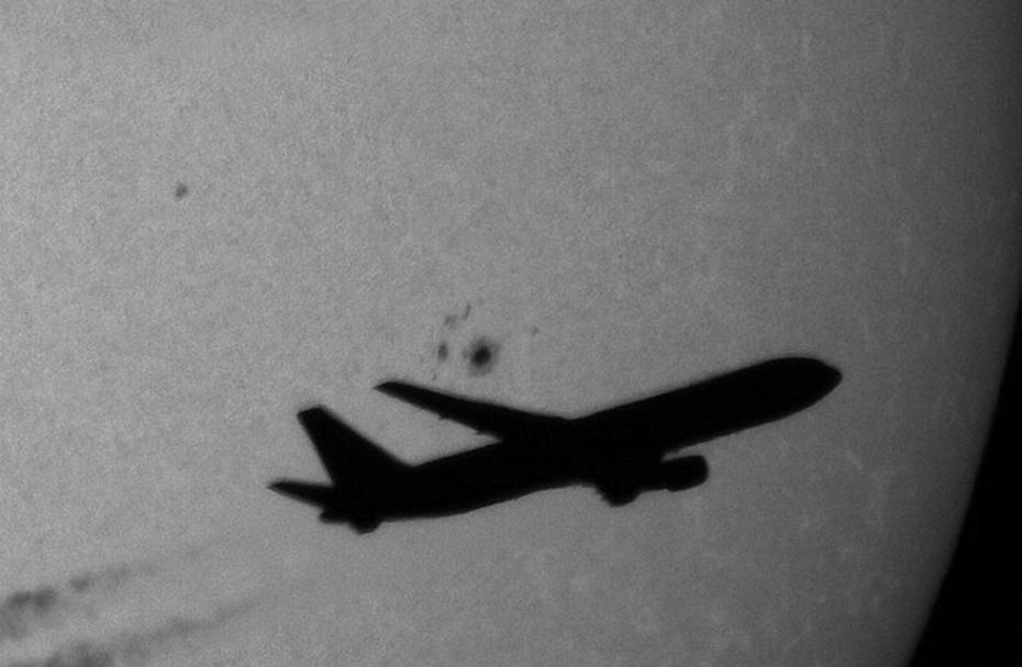 一架飞机划过夜空，其背景中的太阳黑子清晰可见。