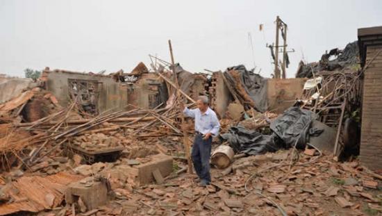 7月7日，在高邮市三垛镇南丰村，一名居民在清理受损房屋。