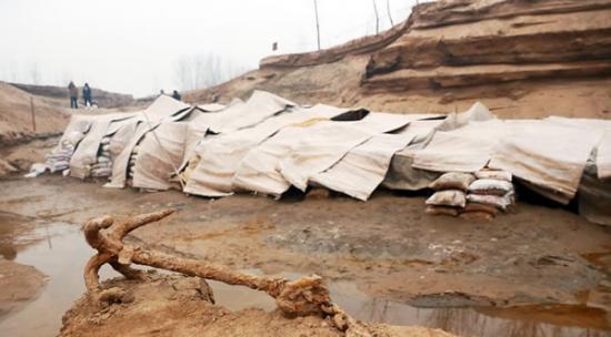 2014年1月6日，河南洛阳古沉船发掘现场，古沉船铁锚从见天日，静静地躺在古船旁。
