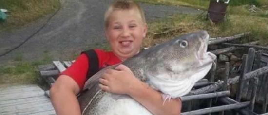 加拿大10岁少年怀抱一只巨大鳕鱼