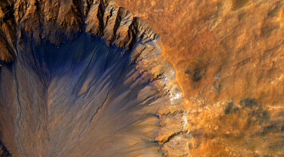 火星的蚀沟和撞击坑发现了盐水痕迹，例如图上这些沿着撞击坑内部边缘的深色条痕。Photograph by NASA/JPL-CALTECH/UNIV. OF AR