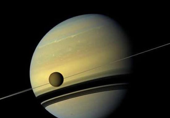 美国宇航局“卡西尼”号飞船发回的彩色图片显示，巨大的土卫六绕行到巨大的土星正面。
