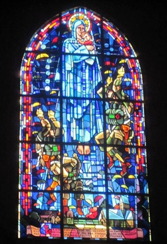 教堂彩绘玻璃描绘伞兵降落于圣母玛莉亚面前，其中一人便是约翰。