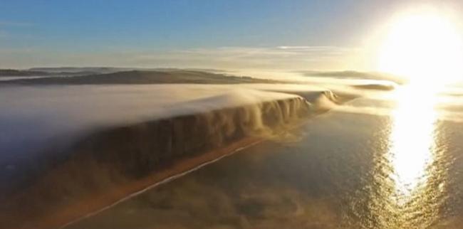 英国多塞特郡西湾出现奇特自然现象 一片白雾在崖边如瀑布向下飞泻