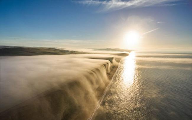 英国多塞特郡西湾出现奇特自然现象 一片白雾在崖边如瀑布向下飞泻