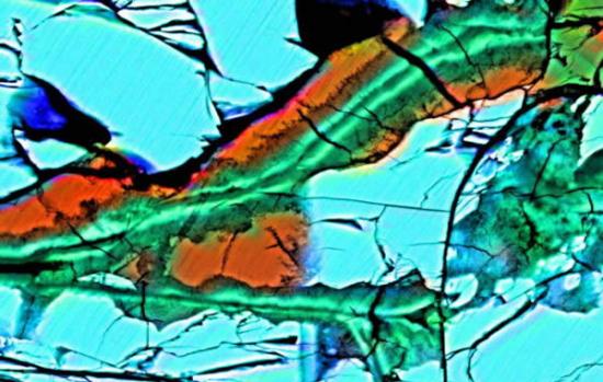 这是拉法耶特陨石切片的伪彩色图像，叠加了X射线图像下的硅(绿色)，铁(红色)以及钙(蓝色)。碳酸盐(橘色)替换了橄榄石(蓝色)，它们两者都被粘土裂隙(绿色)包围