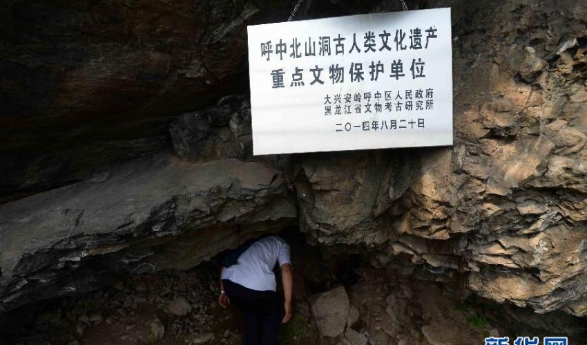 当地文物工作者弯腰进入北山洞洞口（7月23日摄）。