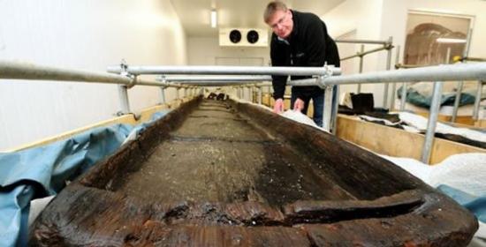 约克考古信任基金会伊恩-潘特正在检查其中一艘青铜器时代木舟，它们挖掘发现于加拿大彼得伯勒地区，被认为是3500年前用于运输货物和乘客