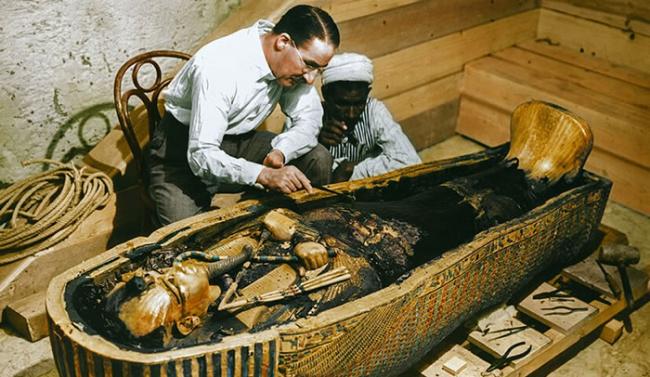 卡特与一名工人正检查棺材内部，彩照显示出镀金木棺的不同颜色。