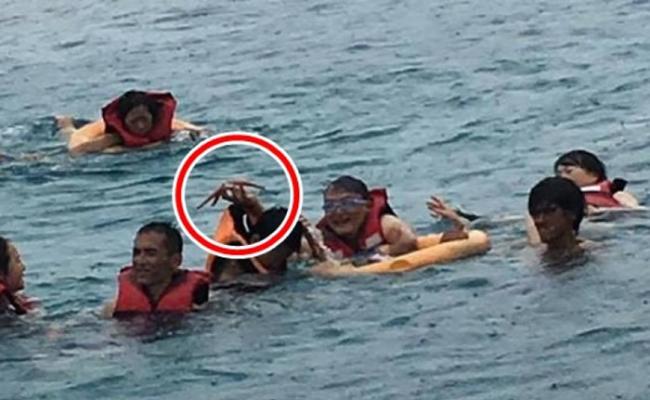 旅客到海中抓海星拍照。